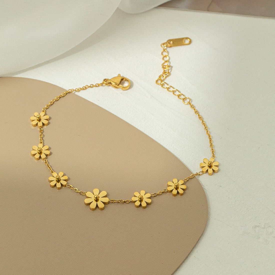 Gold stainless steel floral anklet on a woman's ankle, delicate and hypoallergenic jewelry