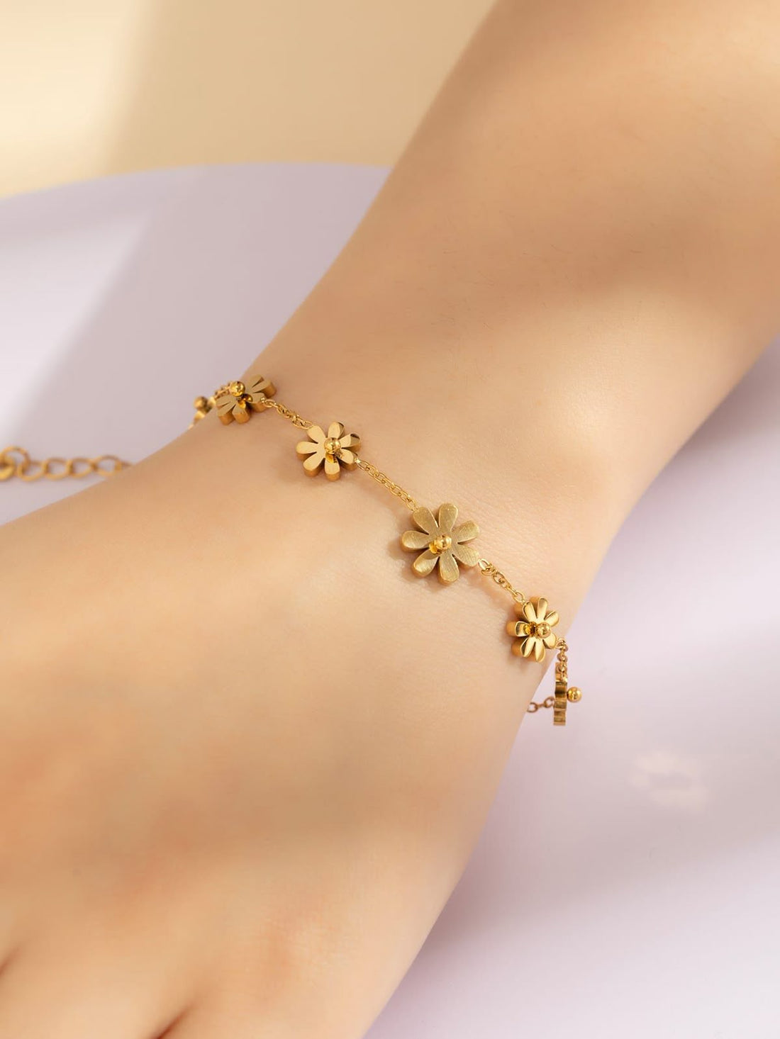 Gold stainless steel floral anklet on a woman's ankle, delicate and hypoallergenic jewelry