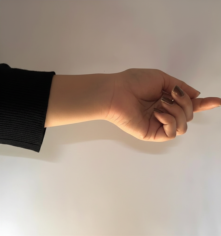 Woman's hand with painted nails in black sleeve, posed against plain background